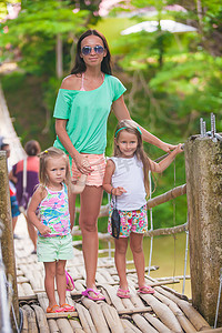 年轻的母亲和她的小女儿们在菲律宾洛博克河上的吊桥上