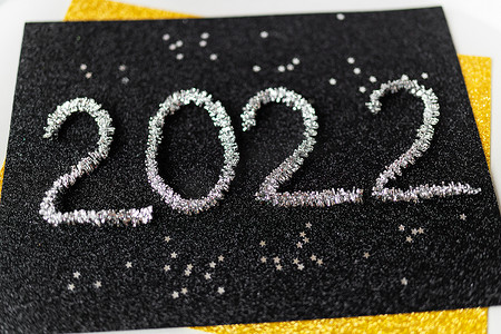 2022 年是用黑色背景上的新年银色金属丝和银色星星书写的。