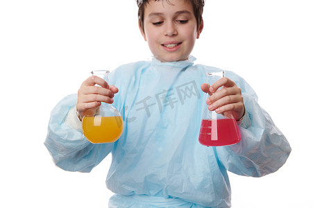 有选择地关注穿着实验室大衣做实验的学童手中装有彩色化学品的实验室玻璃器皿