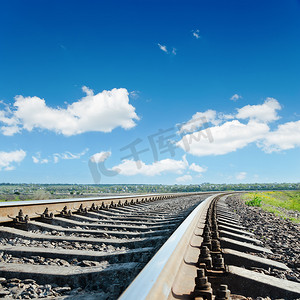 蓝色多云天空下通往地平线的铁路