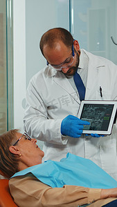 正牙医生使用平板电脑向患者解释牙科 X 光片
