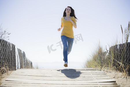 在海滩人行道上奔跑的女孩