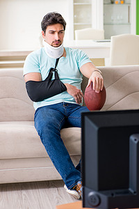 颈部和手臂受伤的男子在电视上看美式足球