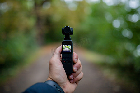 拿着 DJI Osmo 袖珍相机拍摄模糊森林的风景