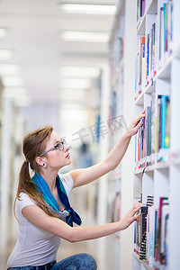 漂亮的女大学生在图书馆里找书