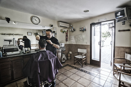 在西班牙安达卢西亚哈恩省萨比奥特的一家理发店里，理发师用剃刀给年轻人剃须