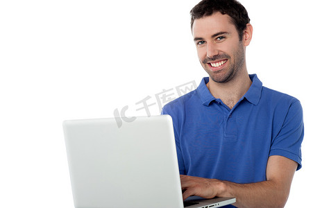 在膝上型计算机上工作的聪明的微笑的人
