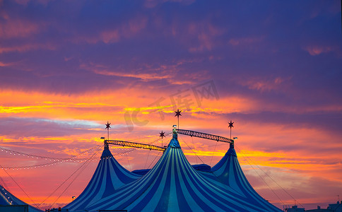 在五颜六色的剧烈的日落天空的马戏团帐篷