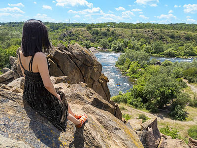 布格摄影照片_一位年轻女子坐在岩石上，看着南布格河风景如画的风景。 