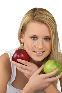 拿着红色和绿色苹果的年轻金发女人