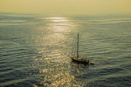帆船大海摄影照片_孤独的帆船在 thyrrenean 海的日落中航行