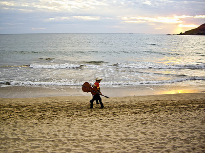 墨西哥流浪乐队在日落时分沿着海滩步行回家