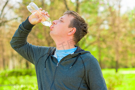 喝水的男人摄影照片_一个男人从小瓶子里喝水的水平肖像