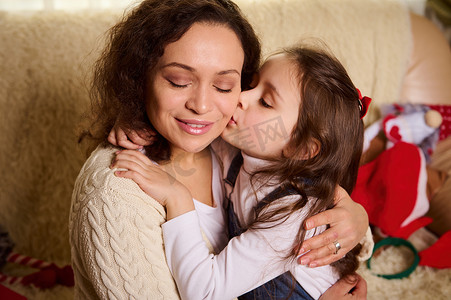 可爱的小孩，可爱的女婴，拥抱和亲吻她慈爱的母亲的可爱的女儿，在圣诞节家庭内部