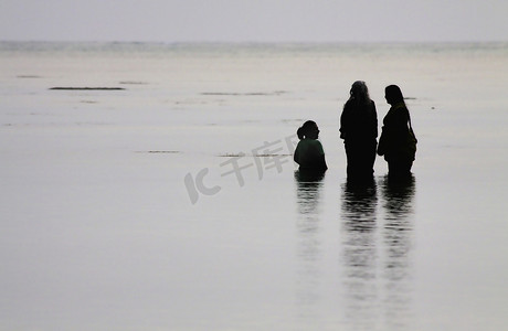 不平静的大海摄影照片_哈夫洛克岛，安达曼群岛，印度。2012 年 1 月 31 日。三名不知名的印度妇女在海上沐浴