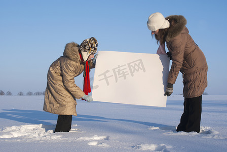 在冬天雪地里拿着白色海报的女孩