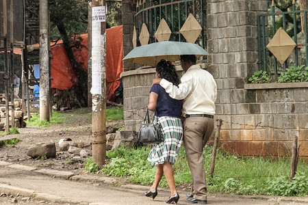 一对夫妇撑着雨伞走在亚的斯的街道上