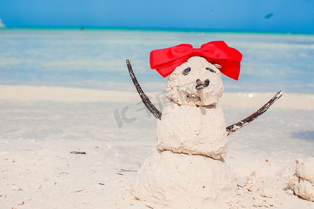 白色加勒比海滩上带蝴蝶结的小沙雪人