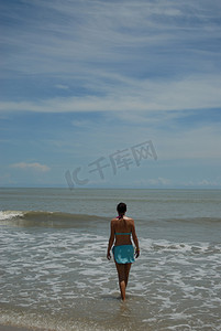 美丽高大的黑发女人在海滩上的股票照片