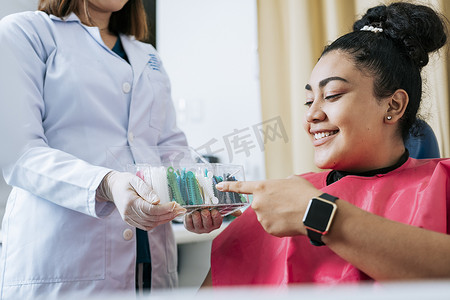 正畸病例摄影照片_牙科病人选择牙套，有牙医的病人选择彩色橡皮筋。