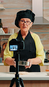 拍摄烹饪视频博客的老妇人