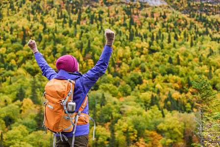 成功赢家女性徒步旅行者在秋天的大自然中为山上的幸福和快乐欢呼。