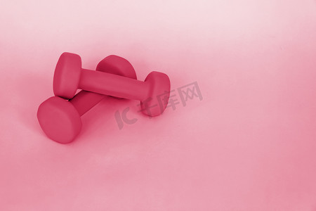 运动仪器测量摄影照片_粉红色背景上运动的绿色哑铃。