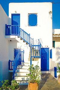 希腊村庄狭窄街道上带蓝色门窗的传统房屋