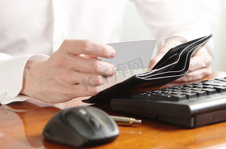 电脑键盘上有钱包和银行卡的商人的手