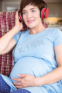 颠簸摄影照片_孕妇将耳机放在颠簸处