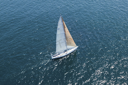 在平静的蓝色海洋中，从高处俯瞰一艘帆船