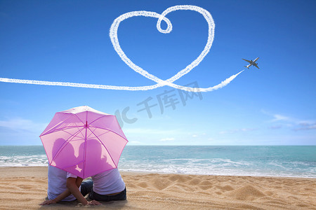 年轻情侣在沙滩上用雨伞浪漫接吻