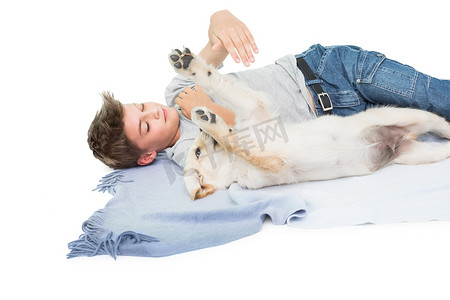 男孩躺在毯子上和狗玩耍