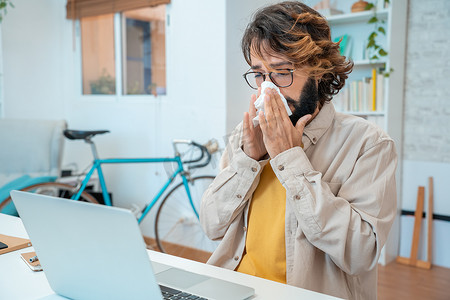 年轻人在工作中生病流感过敏打喷嚏用纸巾擦流鼻涕