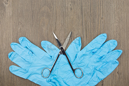 银色手术剪刀和蓝色橡胶手套
