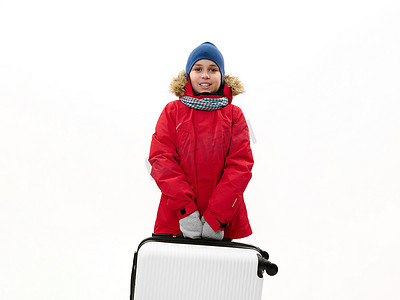 免费青少年摄影照片_身穿红色派克大衣和蓝色帽子的中东少年，带着手提箱，在白色背景中被隔离，有免费广告空间