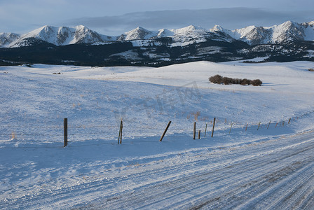 美国蒙大拿州加拉廷县的布里杰山脉、乡村公路和积雪覆盖的牧场在一个冬天的早晨