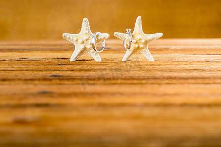 木桌上有两只海星的两个结婚戒指