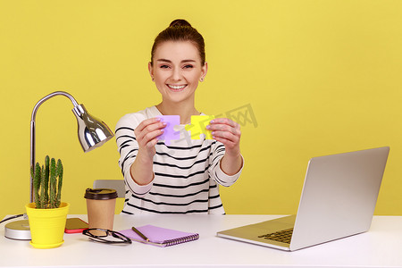 工作难题摄影照片_微笑的女人将两块彩色拼图放在一起，轻松解决工作中的难题。