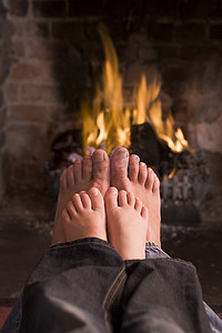 父亲和儿子的脚在壁炉前取暖