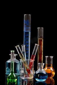 各种带有彩色试剂的实验室烧瓶，黑色背景中的吸管
