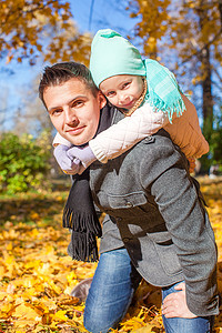 阳光明媚的日子里，有快乐父亲的可爱小女孩在秋季公园玩得开心