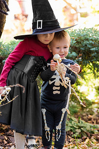 万圣节派对上穿着女巫服装的小女孩和穿着骷髅服装的男孩