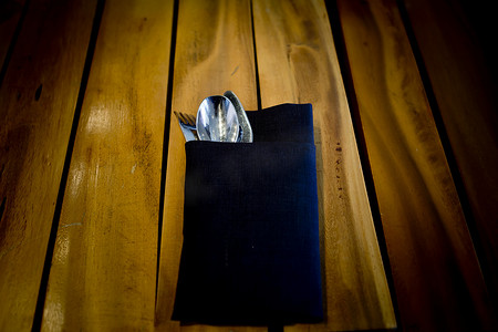木桌背景中深蓝色布料的叉子和勺子