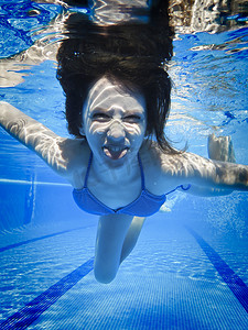 动物表情摄影照片_青少年在游泳池水下游泳，脸上带着滑稽的表情