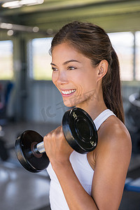 亚洲女性在健身房用自由重量训练二头肌，举哑铃进行手臂锻炼