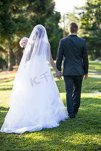 新娘的摄影照片_新娘和新郎手牵手在花园里