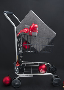 黑纸圣诞礼盒放在带红球的购物篮里