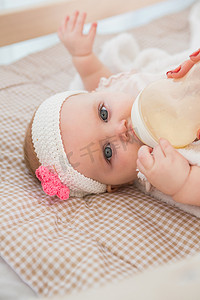 喝她的婴儿奶瓶的快乐可爱的小女孩