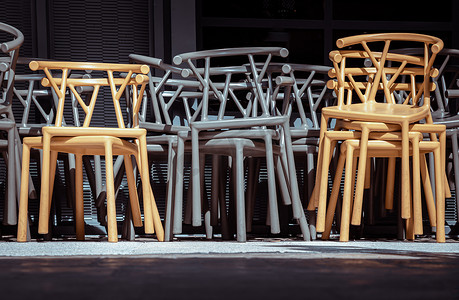深绿色装饰摄影照片_阳光明媚的日子里，咖啡馆露台旁边放着一堆深绿色（卡其色）和黄色塑料椅子。